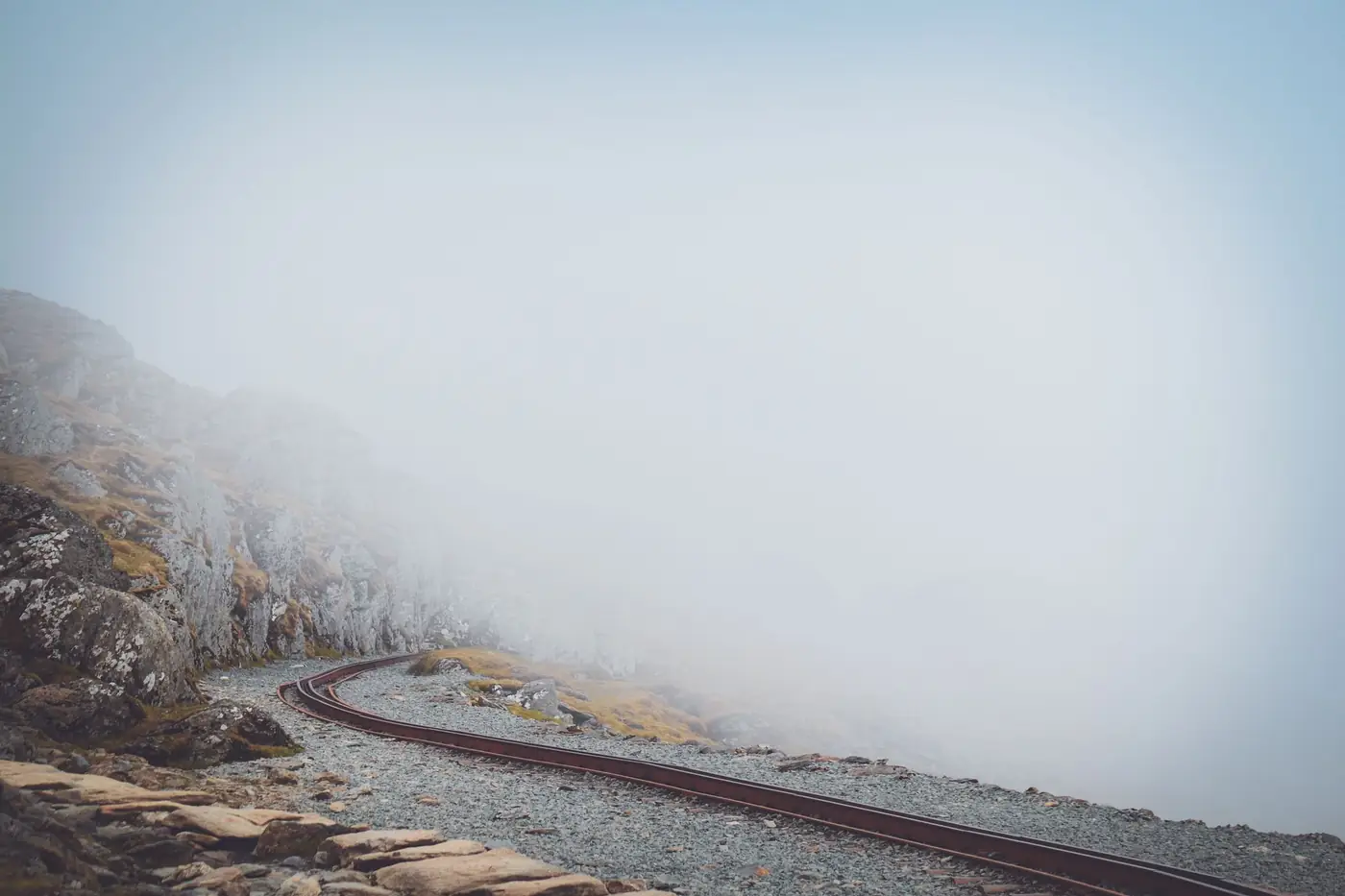 Mist over een spoorlijn tussen de rotsachtige bergen van Wales
