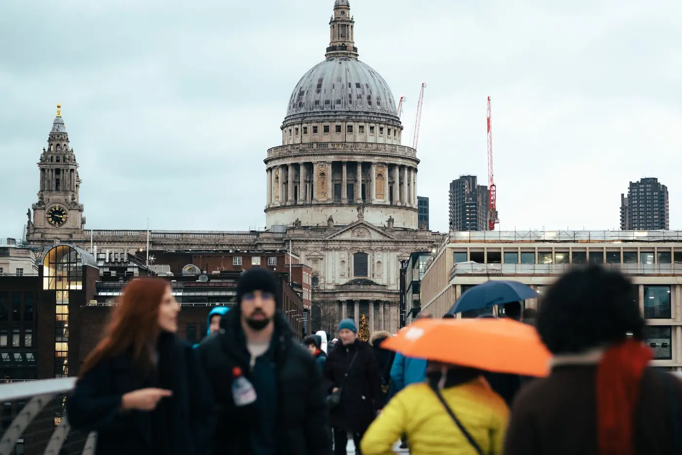 Voetgangers op een brug met de koepel van een kathedraal op de achtergrond in Londen
