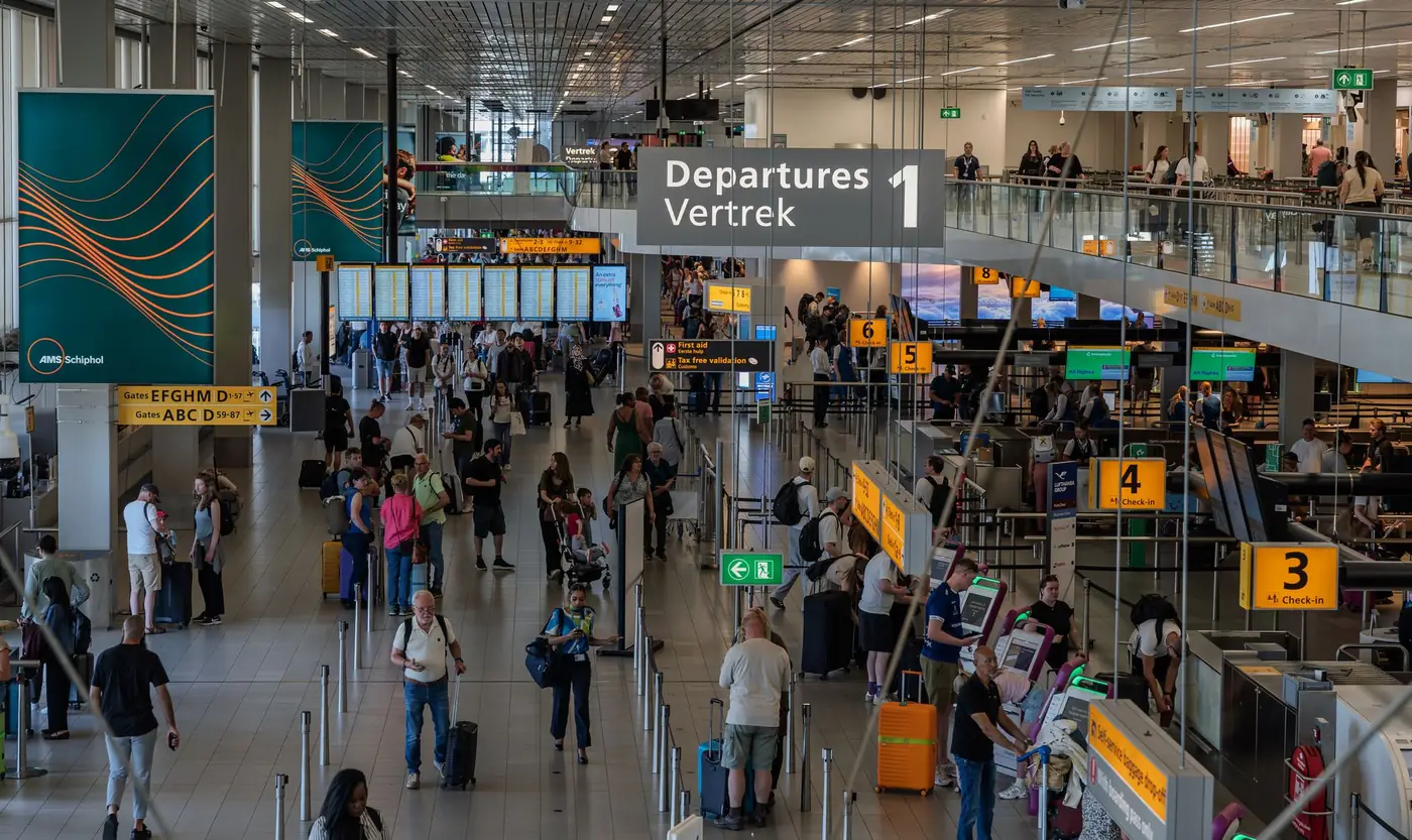 Reizigers met bagage in een drukke vertrekhal van een luchthaven