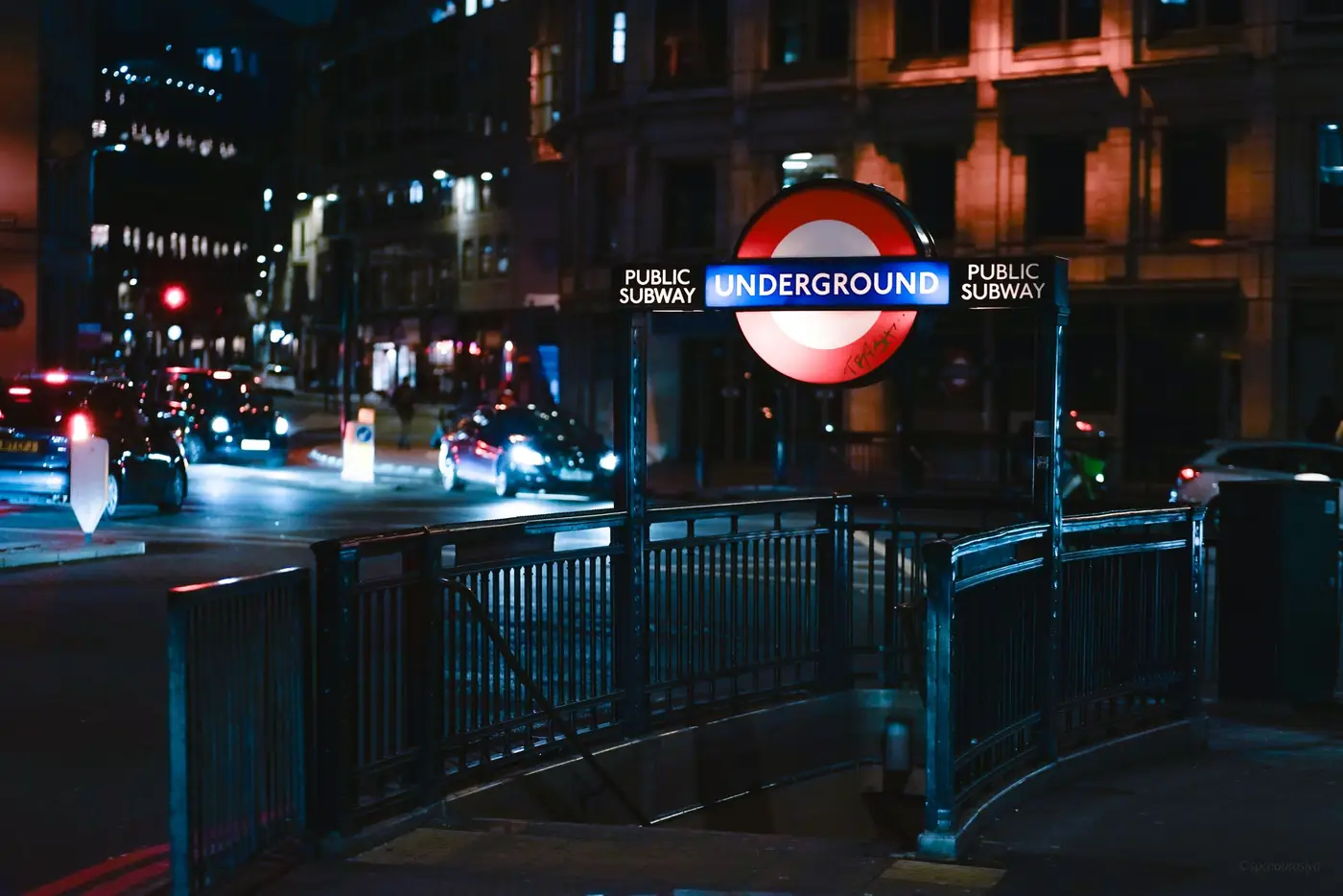 Verlichte ingang van een metrostation in Londen bij avond