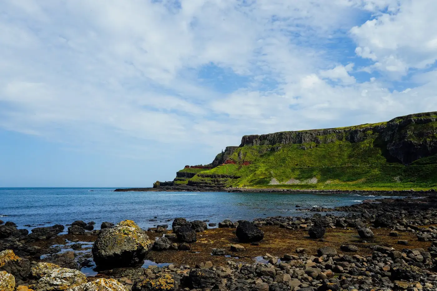 Dramatic coastal landscape of Giant's Causeway with basalt columns and blue sky.