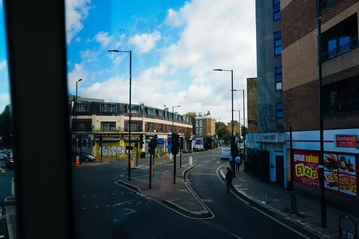 City street view with graffiti, brick buildings, and street signs under a bright blue sky.
