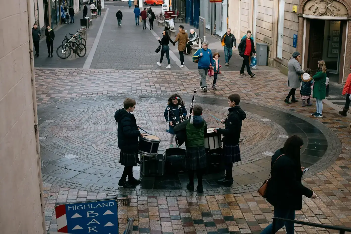 Scottish teenage musicians wearing traditional clothes and playing drums and bagpipe on street on autumn day