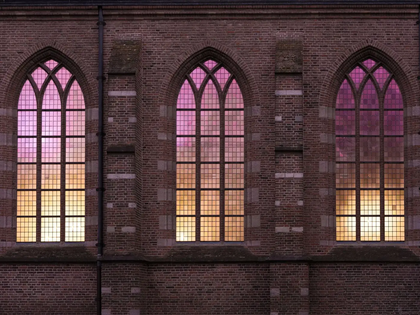 Stunning stained glass windows of a Gothic church in Naarden, Netherlands illuminated by sunset hues.