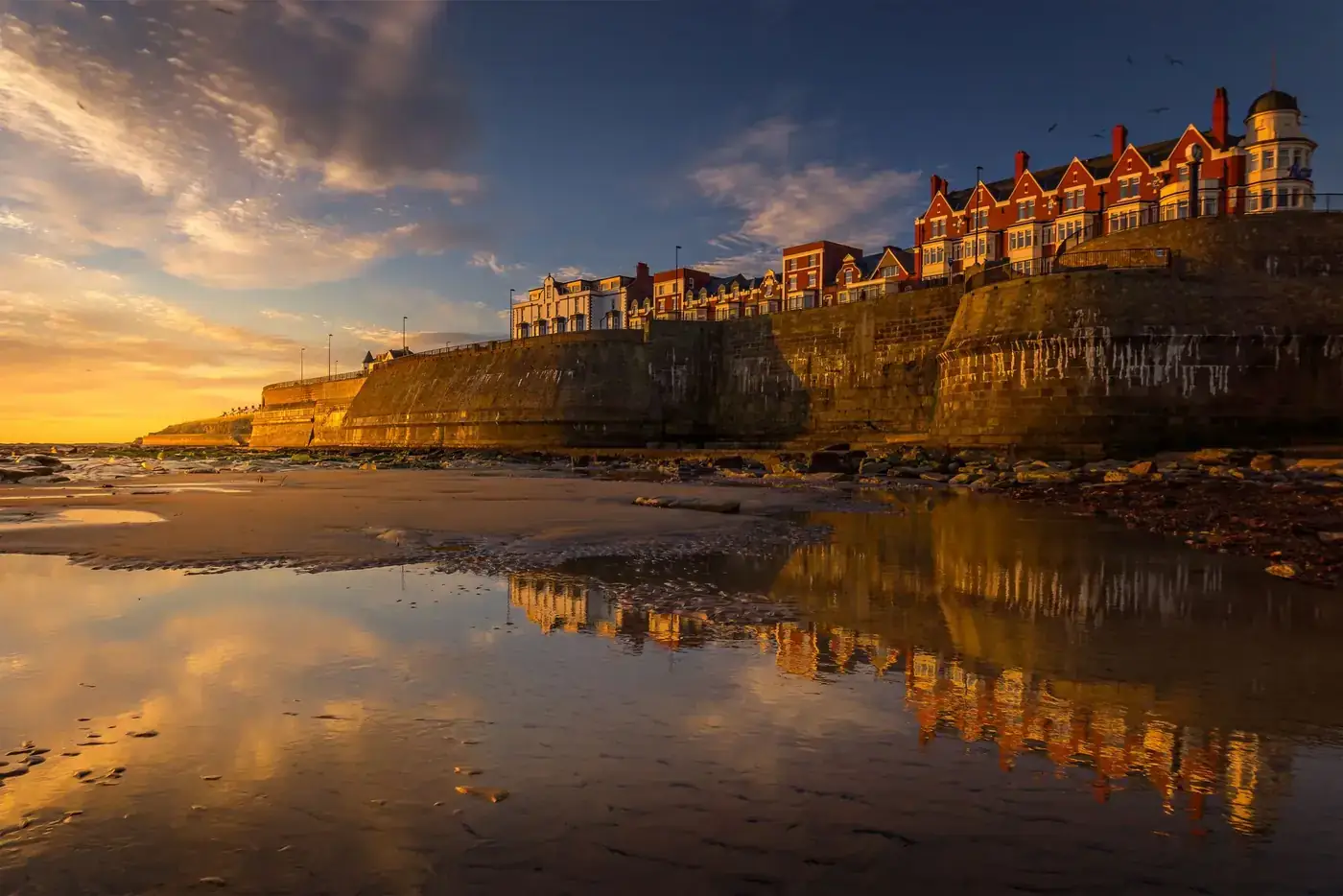 Golden sunset reflection at Whitley Bay seaside, featuring the historic Rex Hotel and waterfront.
