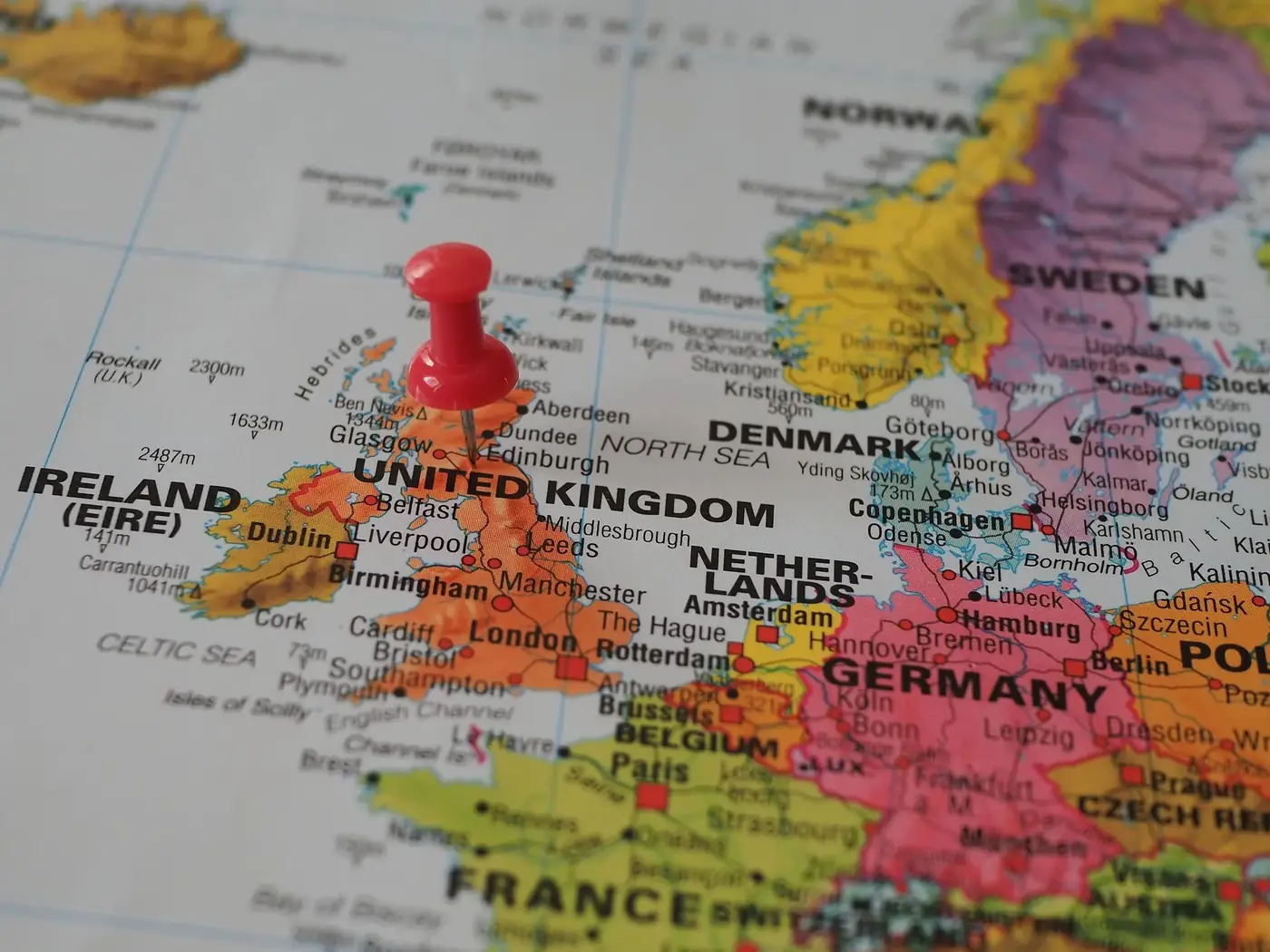Close-up of a European map highlighting the UK with a red pin, perfect for geography themes.