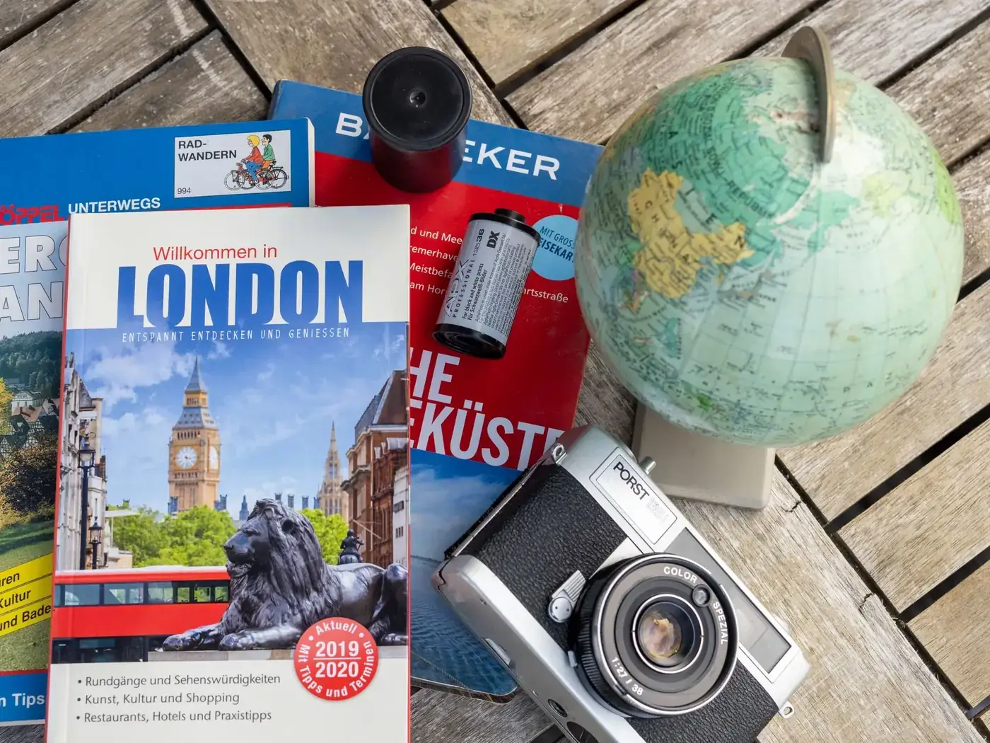 Flat lay featuring London travel guide, vintage camera, and globe, ideal for travel theme.