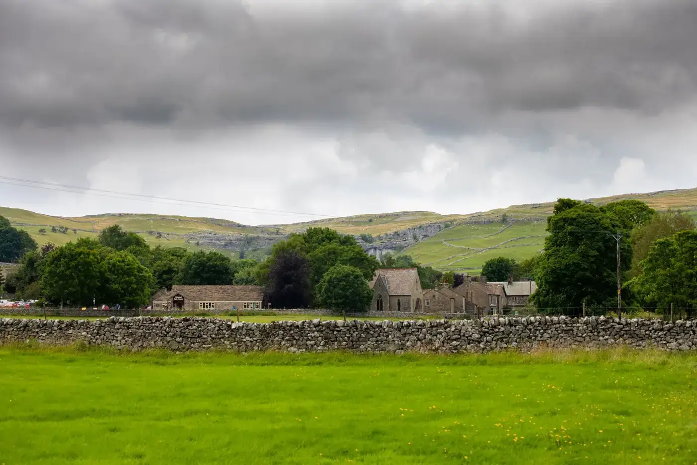Scenic English rural landscape with stone walls and rolling hills under dramatic skies.