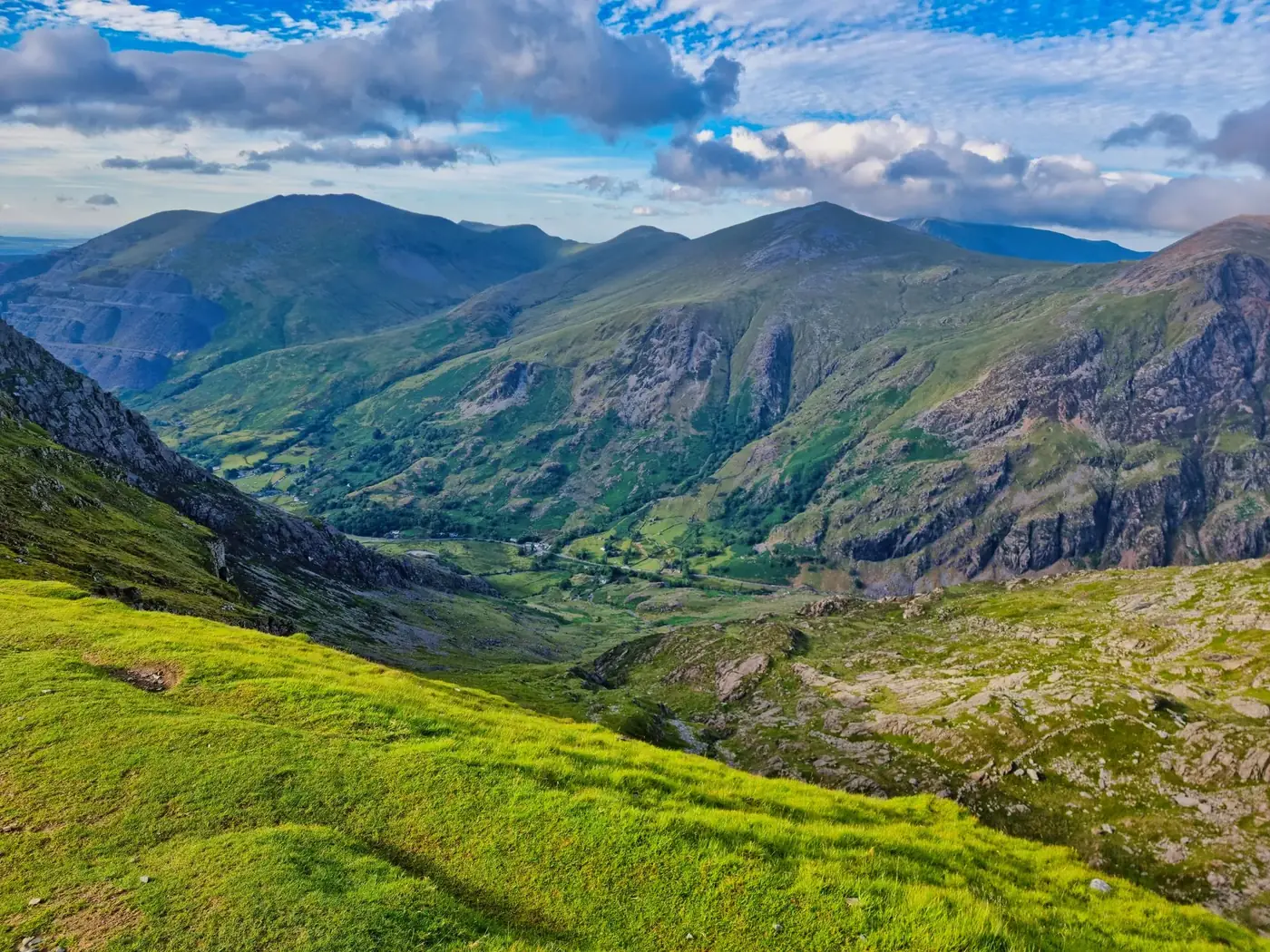 Breathtaking view of rugged mountains and green valleys under a vibrant blue sky.