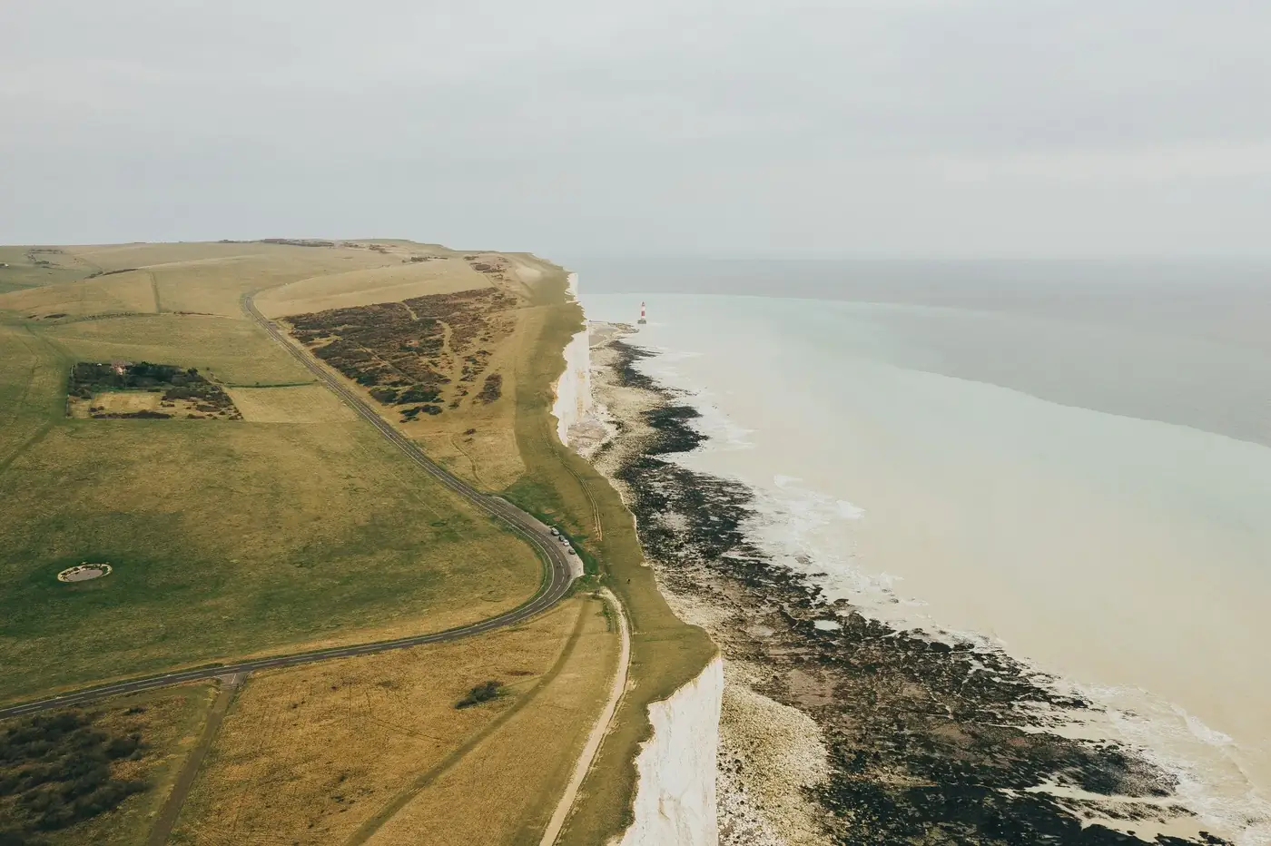 Aerial view of picturesque coastal cliffs with a winding road along the shoreline.